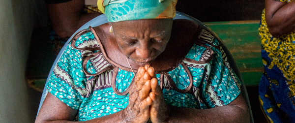 An African woman bowing her head and praying.